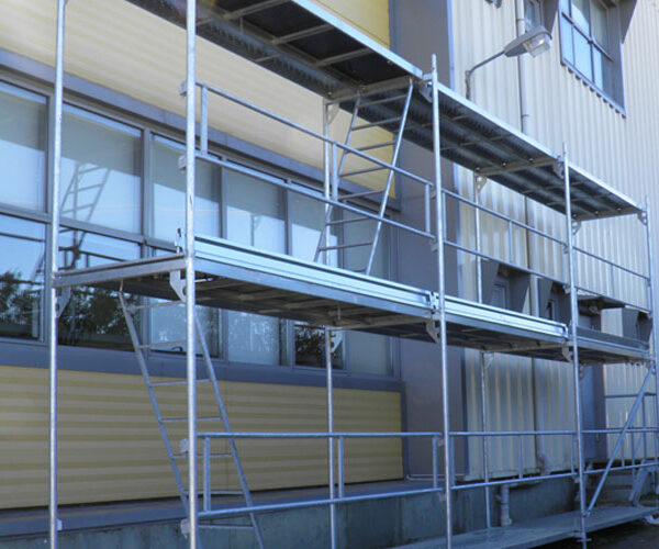 Αρθρωτή σκαλωσιά σε βιομηχανικό κτίριο με προστατευτικά κιγκλιδώματα.
